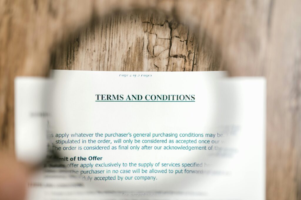 A magnifying glass highlighting terms and conditions text, representing how Ariscu ISO certification software simplifies complex legal and compliance requirements.