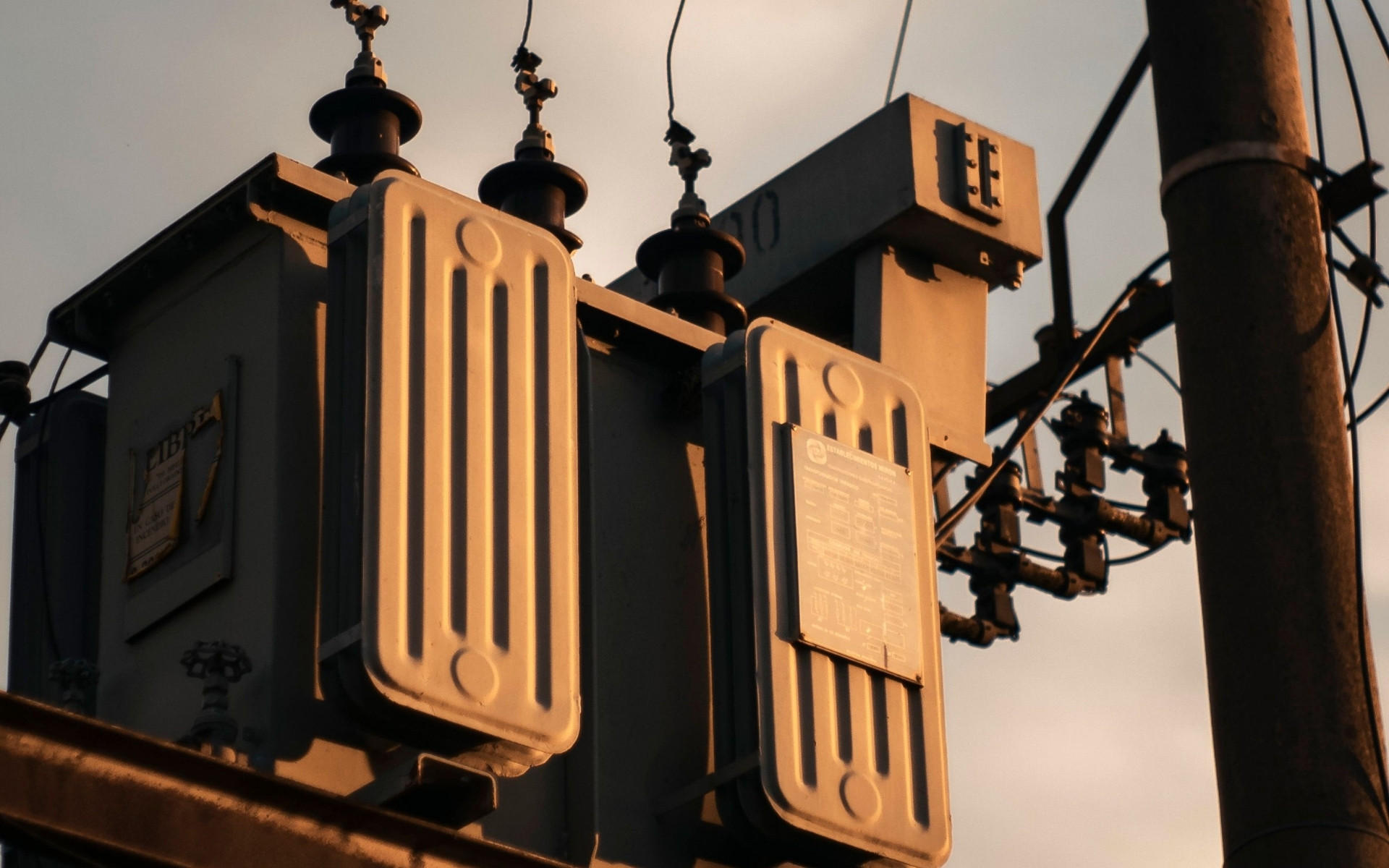 An outdoor electrical transformer mounted on a pole against a sunset sky. Learn how to stay compliant with GNR 549 of 2014 and avoid fines to phase out PCB-containing transformers in South Africa.